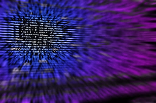 An image of computer code that blurs into a blue and purple ombre.