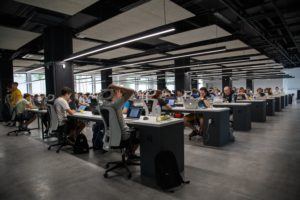 An open concept office filled with people working at their desks.