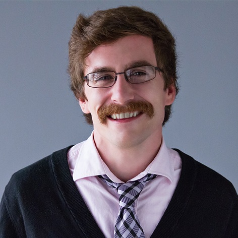 Picture of Devin Culclasure. He wears a pink shirt, black & white tie, and a glorious mustache.