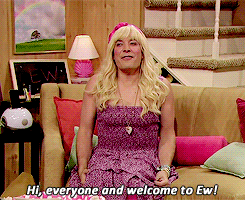 GIF of Jimmy Fallon in a pink dress and blonde wig. Caption says "Hi everyone and welcome to Ew!"