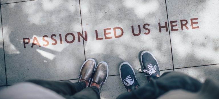 A picture looking down at people's shoes. The pavement reads "Passion Led Us Here".