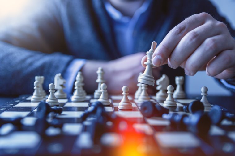 A person playing chess. There is a red light flare at the bottom of the photo.