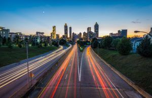 Long exposure photo of traffic on a highway and a city skyline in the distance.