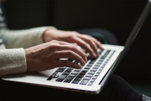 A picture of a woman's hands typing on a laptop.
