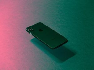 Image of an iPhone floating above a pink and teal ombre surface.