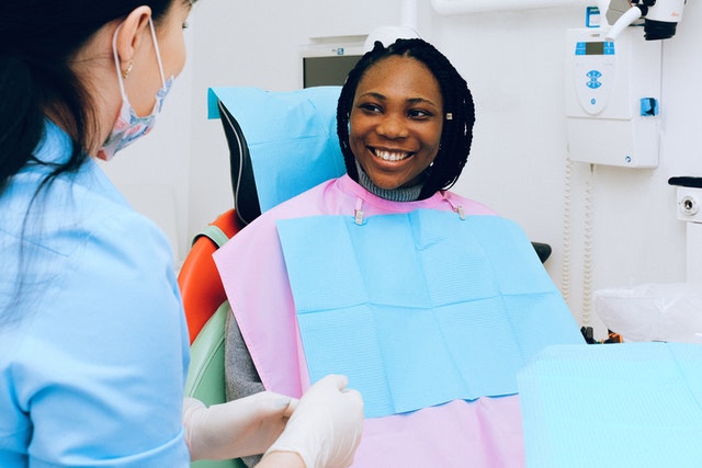 A patient with black hair listens as an orthodontist explains her treatment plan.