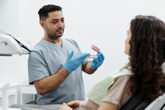 An orthodontist shows a patient a dental model and explains their treatment plan to them.