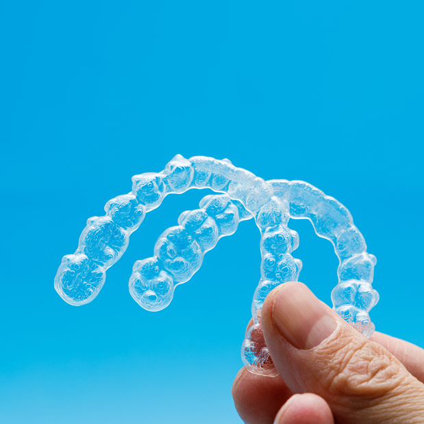 A White Hand Holding Up Clear Retainers