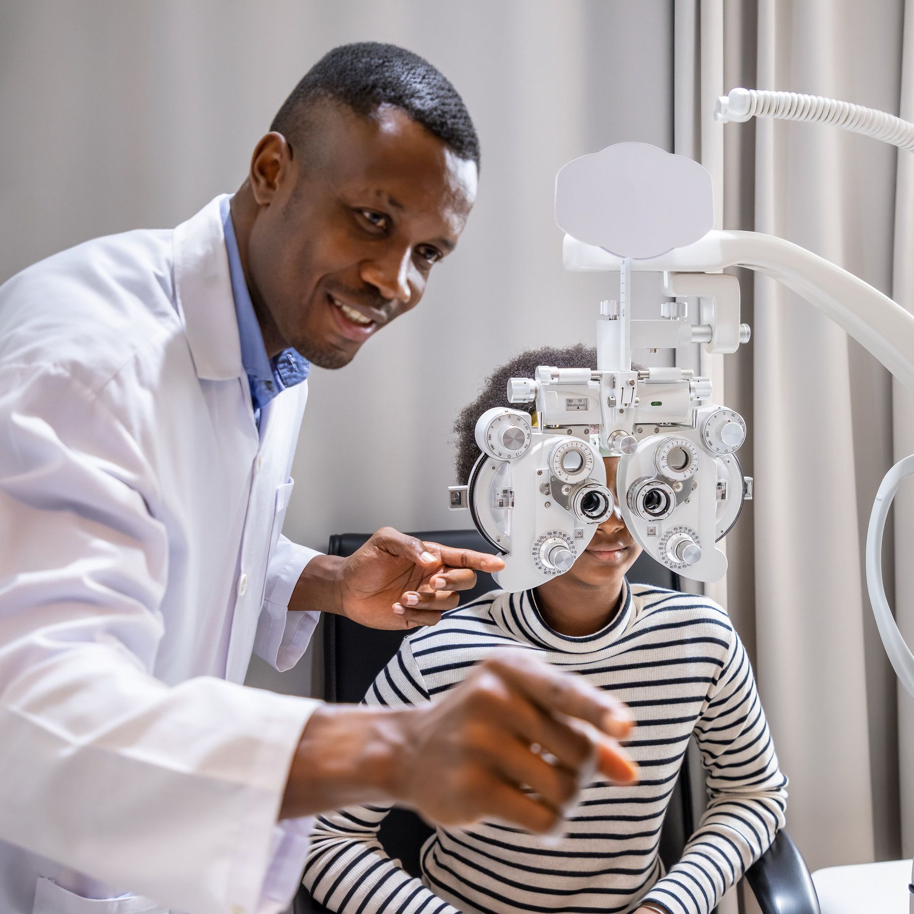 African Young Woman Girl Doing Eye Test Checking Examination With Male Man Optometrist Using Phoropter In Clinic