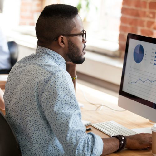 African American man talking by phone about report Serious African American man in glasses talking by phone about economic report with pie diagrams, marketing plan, business results, using computer, applications, looking at screen